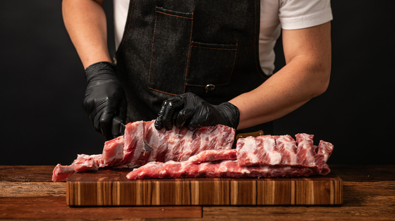 A butcher preparing a rack of spare ribs.