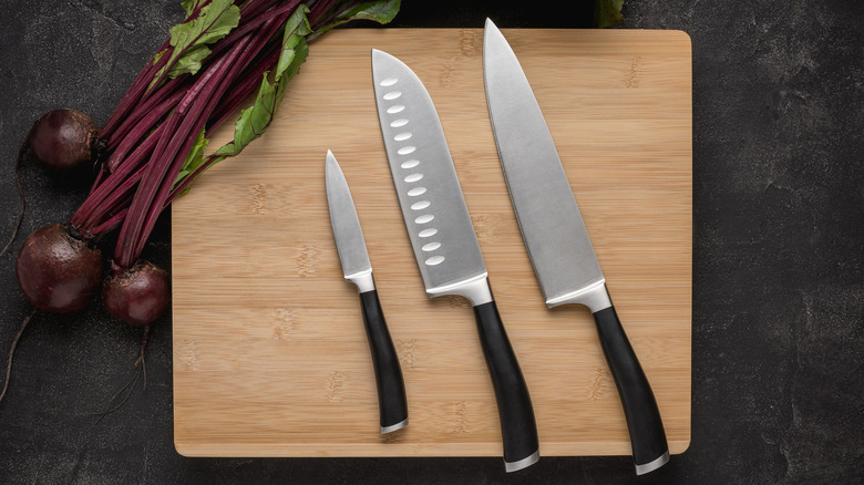 Three knives on cutting board with beets