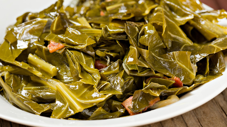 Cooked collard greens with bacon on white plate