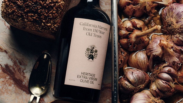 A bottle of Heritage Extra Virgin Olive Oil alongside food.