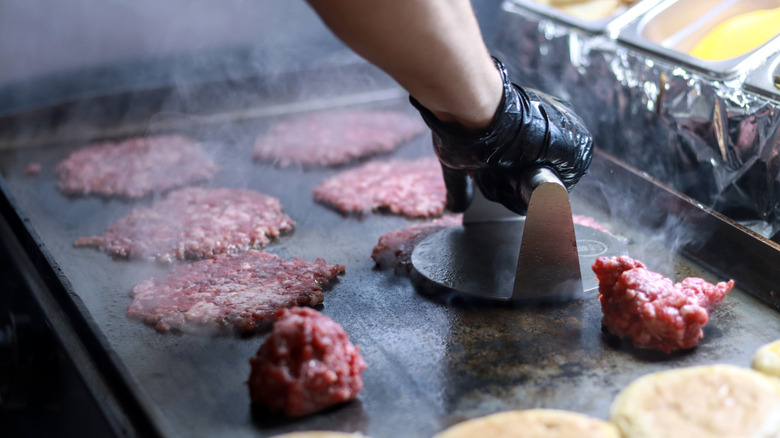 Smash burgers cooking on a griddle