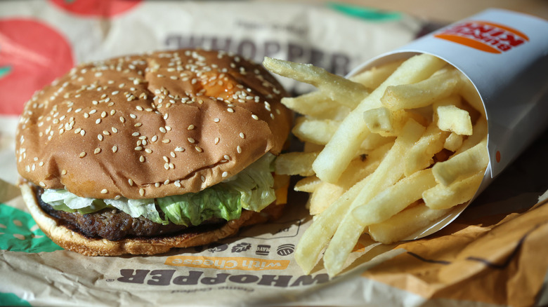 A Whopper sits next to Burger King fries on an open burger wrapper.