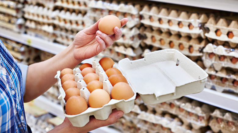 person holding eggs at supermarket
