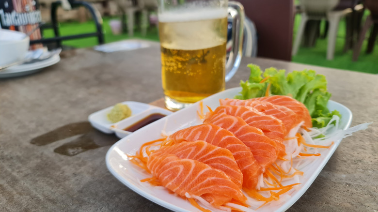 A plate of sashimi and beer.