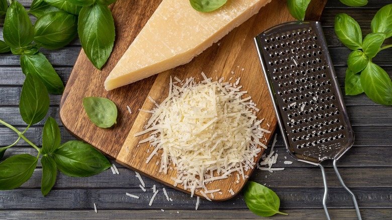 Shredded cheese and block of cheese on cutting board