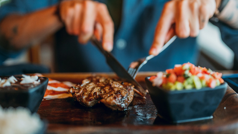 diner cutting into a steak