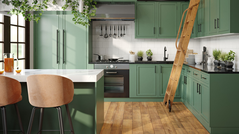 A kitchen with green cabinets and wood floors