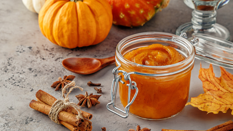 Glass jar of pumpkin butter with pumpkin and spices