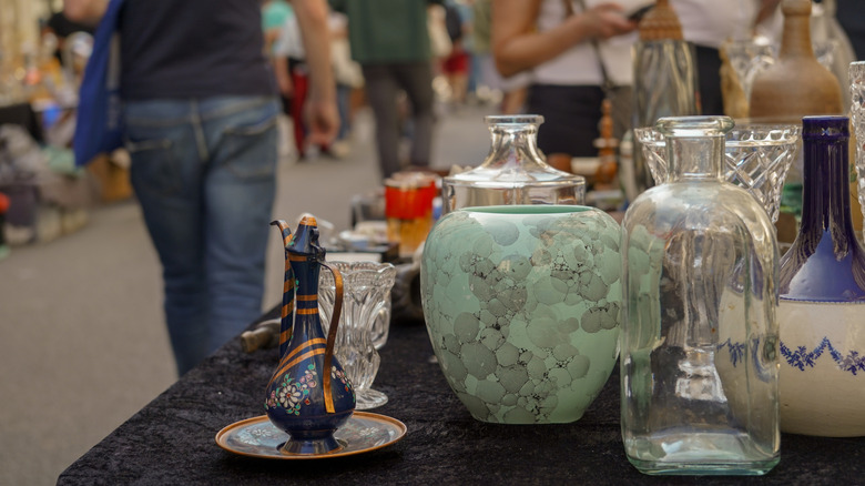 Kitchen items on display in a second-hand shopping venue, with shoppers passing in the background