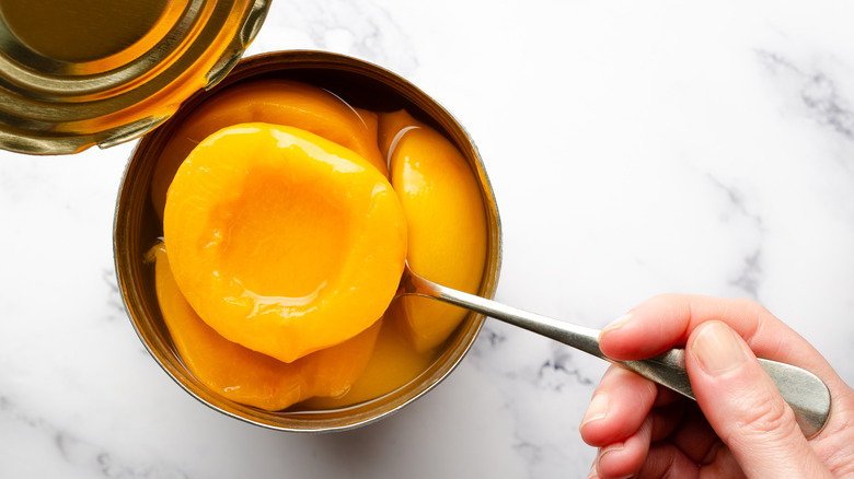 person taking a canned peach out of the jar