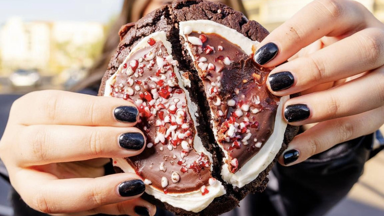 Chocolate holiday cookie with frosting and candy cane pieces from Crumbl
