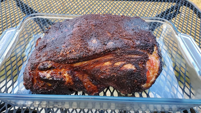 A smoked Boston butt pork shoulder in a glass tray