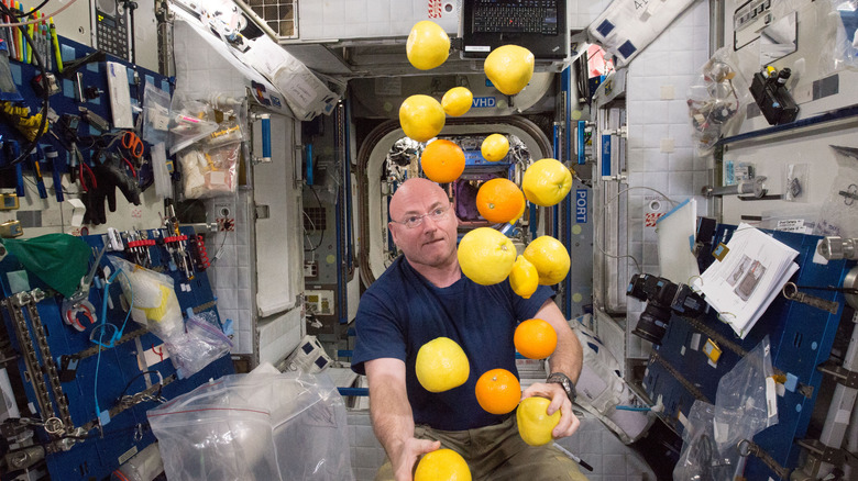 Astronaut gathering floating oranges, lemons, and grapefruits on the International Space Station