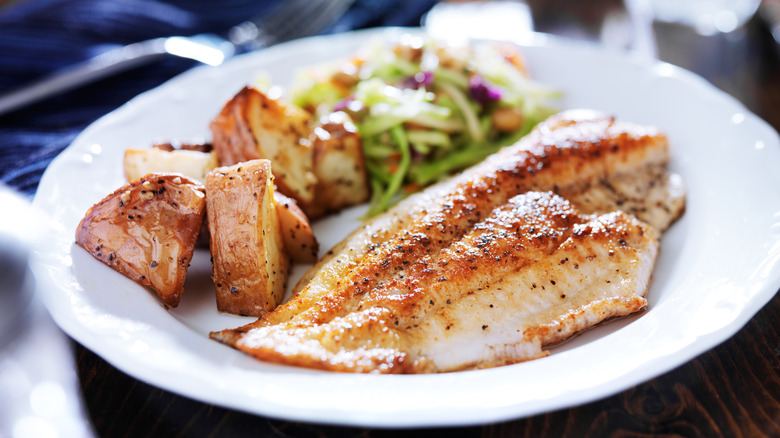 Pan-fried tilapia with potatoes and slaw on plate