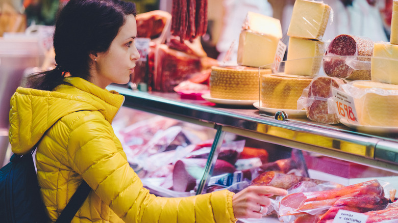 Woman gesturing to cheese and deli display