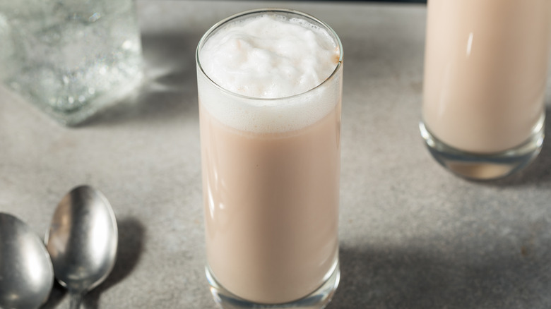 Egg cream drink in a tall glass next to spoons
