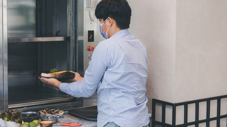 hotel chef uses a dumbwaiter in kitchen