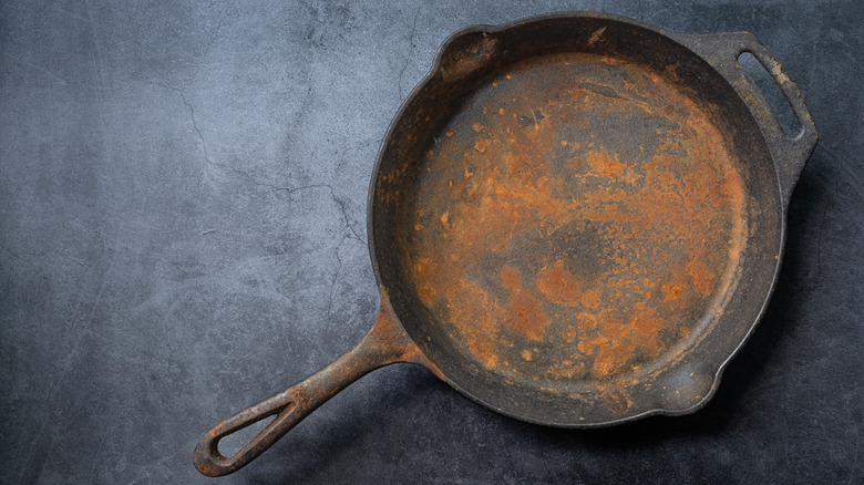 Rusty cast iron pan on dark surface