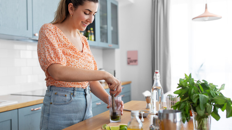 woman muddling a mojito cocktail