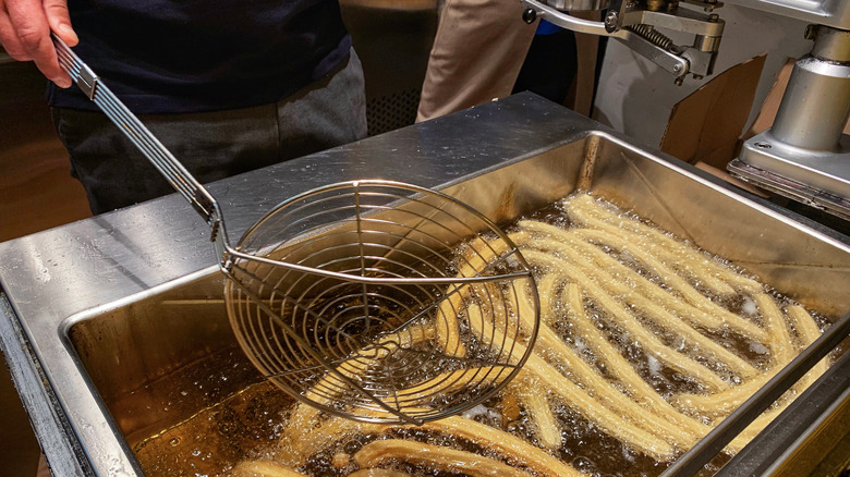 Metal spider strainer with deep-frying oil and churros