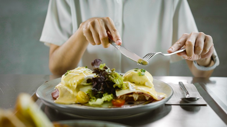 person eating eggs Benedict