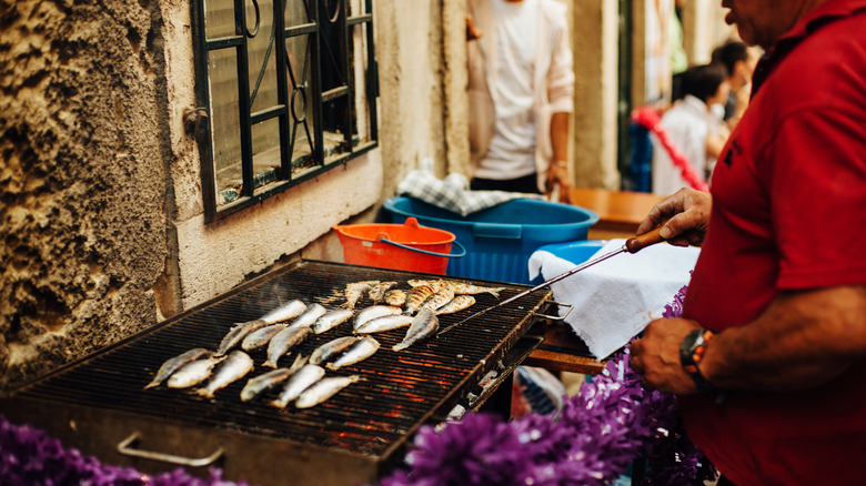man grilling sardines over fire