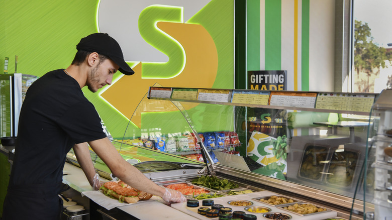 A worker makes sandwiches at a Subway