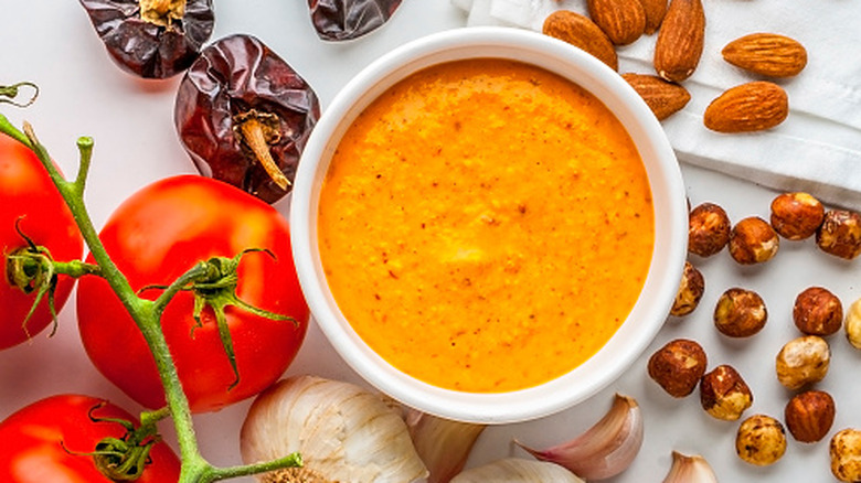 A bowl of romesco sauce surrounded by its ingredients