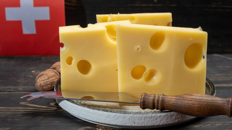 block of Swiss cheese cuts with knife