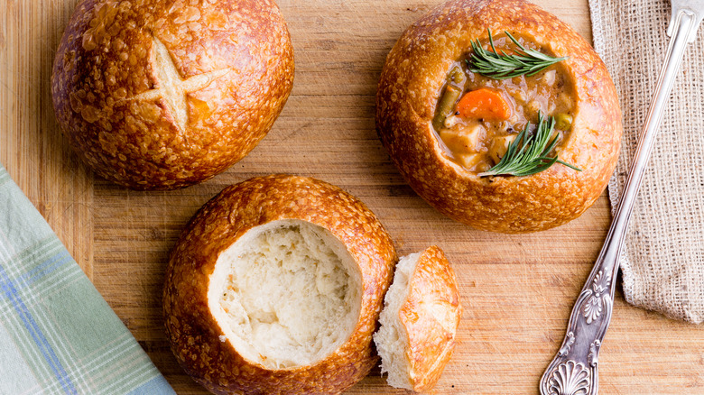 Three bread bowls, one with stew, on board