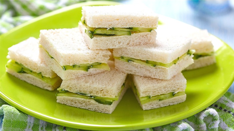 Square cucumber tea sandwiches stacked on lime green plate