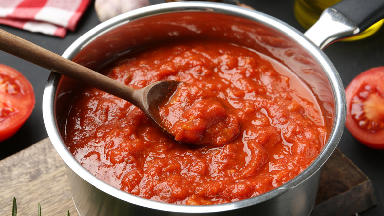 Pot of tomato sauce with wooden spoon.