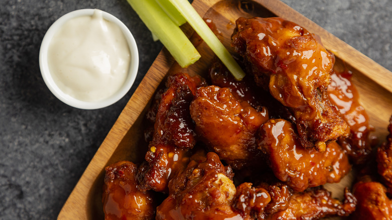 chicken wings on a wood platter with celery and dipping sauce