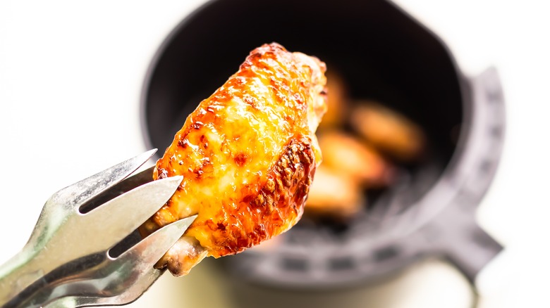 close up on crisp wing with air fryer basket in background