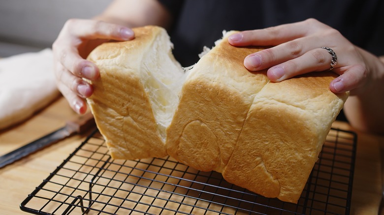 Hands pulling apart a loaf of milk bread