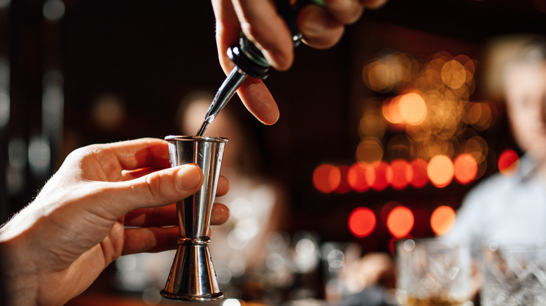 bartender pouring shot in jigger