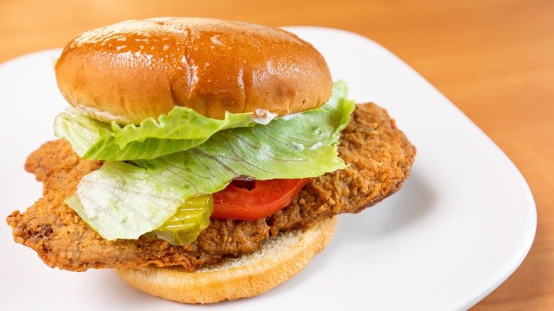 Chicken fried steak with lettuce, tomato, and pickle on a bun