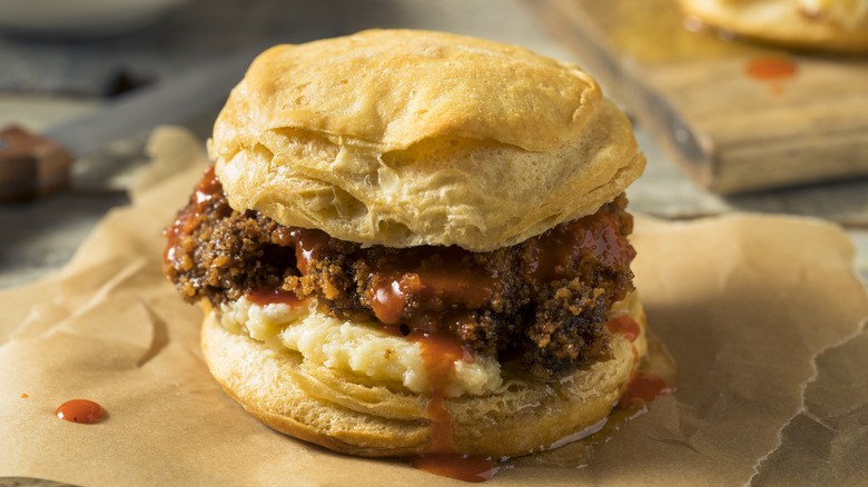 Fried chicken on a biscuit drizzled with hot sauce on parchment