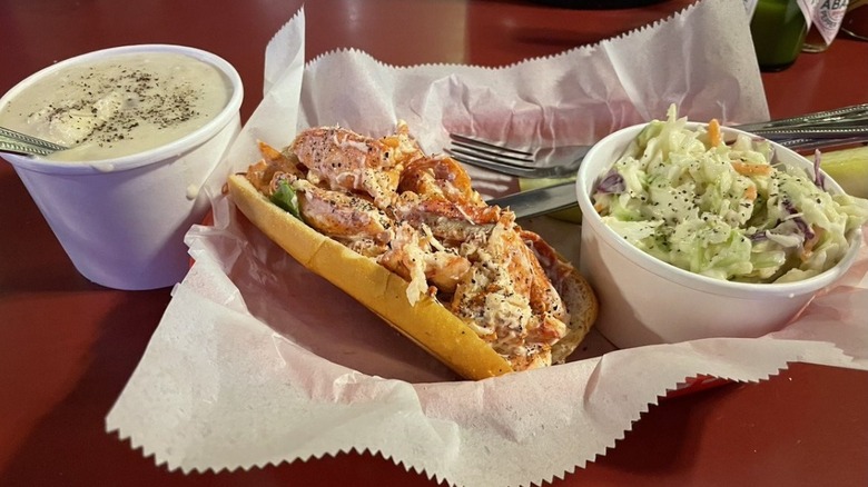 Lightly dressed lobster roll served with cups of slaw and chowder