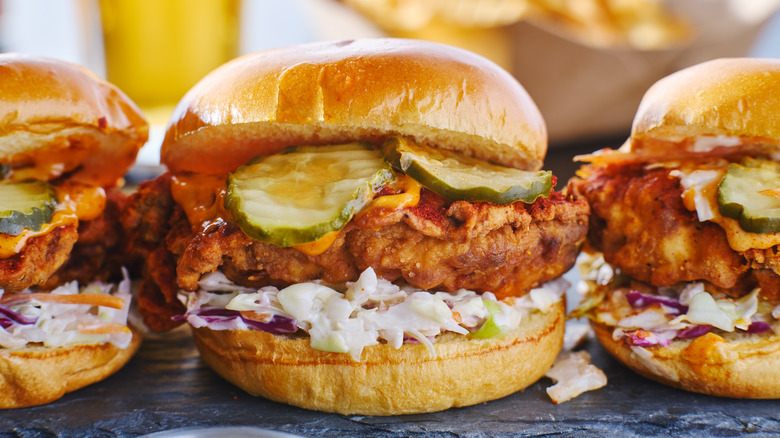 Row of sandwiches with Nashville hot chicken, pickles, and slaw