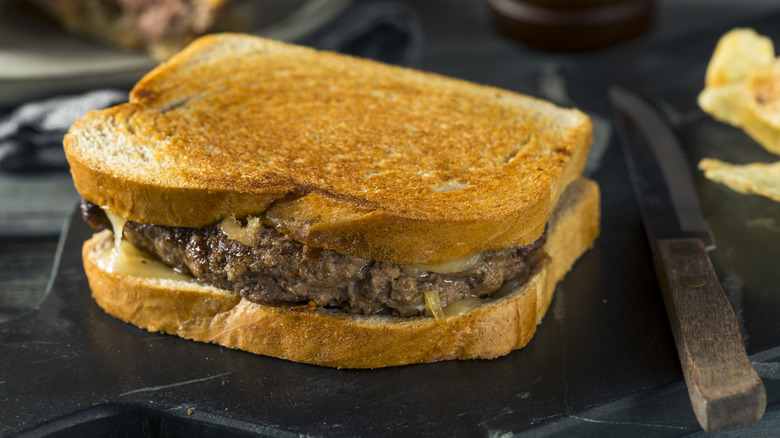 Burger patty with melted cheese and caramelized onions on toasted bread
