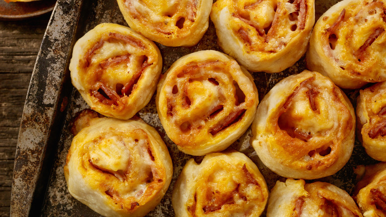 Cheese and pepperoni filled rolls packed tightly on a baking tray