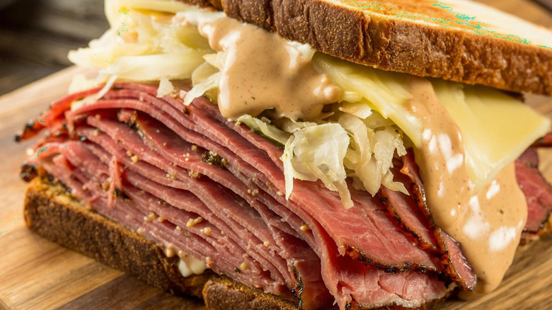 Slices of corned beef with sauerkraut, Swiss cheese, and Russian dressing packed between two slices of bread