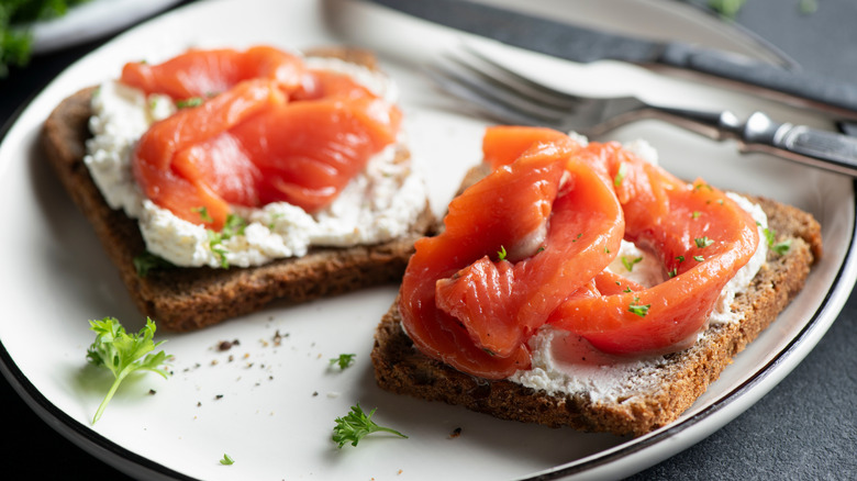 Smokes salmon on toast with cream cheese and herb beside cutlery