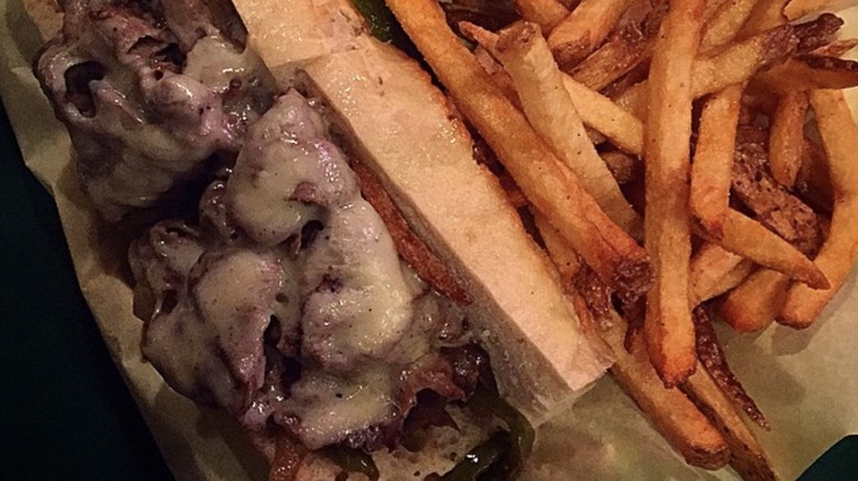 Slow-roasted lamb with melted cheese atop bread served with fries