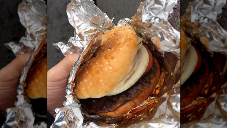 Teriburger with tomato and onion wrapped in aluminum foil