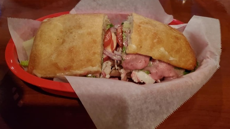 Ham, turkey, tomato, onion, and apple seen on a Vermonter sandwich in a basket