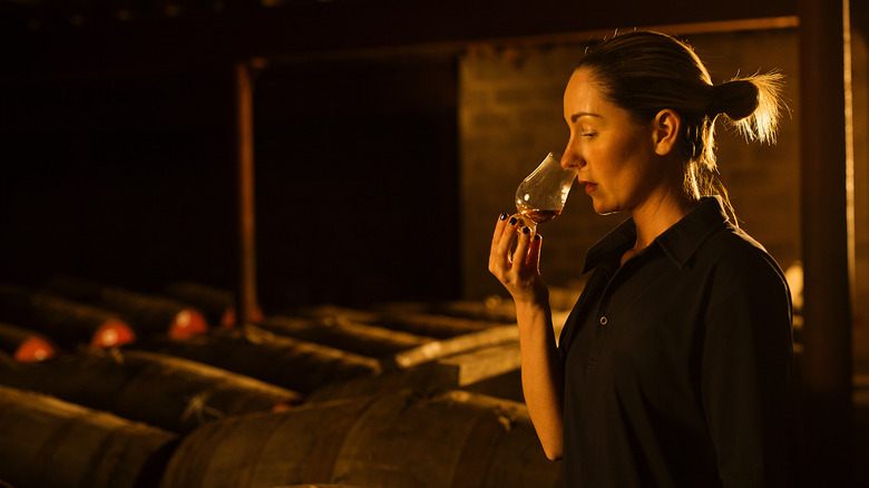 A distiller nosing a glass of whiskey to test it