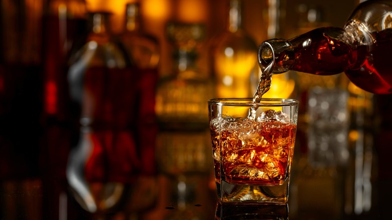 An open bottle of whiskey next to a rocks glass