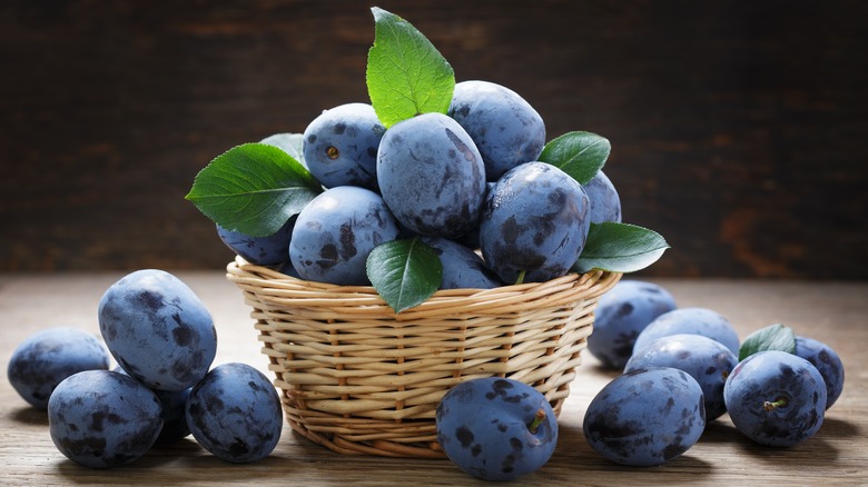 Bowl of plums on wood